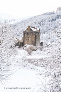 an old castle in the middle of winter with snow on the ground and trees around it