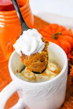 a spoon with some food in it on top of a white cup filled with ice cream