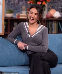 a smiling woman sitting on top of a blue couch