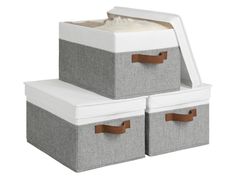 two storage bins with leather handles and fabric liners, one in grey and the other in white