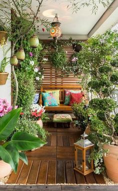 a balcony with potted plants and wooden benches on the floor, surrounded by greenery