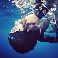 a person in the water with a camera attached to their wrist and wearing a helmet