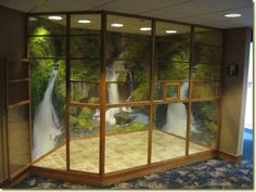 an office with glass walls and waterfalls on the wall behind it in front of a window