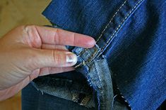 a person with their hand in the pocket of a pair of blue jean pants that is being sewn together