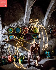 a man sitting in front of a wall with lights on it's face and hands