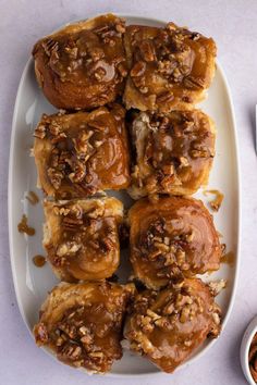 a white plate topped with pastries covered in caramel and pecan toppings