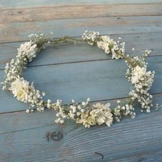 a wreath made out of dried flowers sitting on top of a wooden floor next to a wall