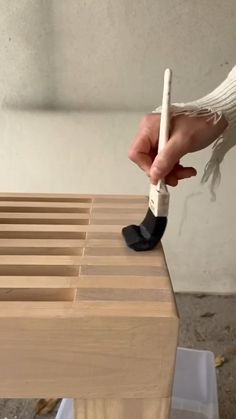 a person is using a brush to clean a wooden table with white paint on it