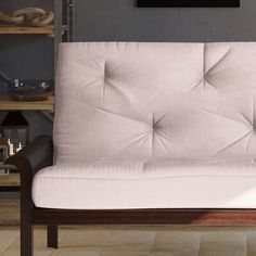 a white futon couch sitting on top of a wooden floor next to a wall