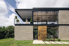 a modern house with large glass windows and wooden doors on the outside wall, surrounded by green grass