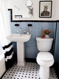 a white toilet sitting next to a sink in a bathroom under a framed picture on the wall