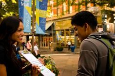 a man and woman standing next to each other in front of a building with signs on it