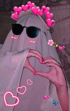 a person in sunglasses making a heart shape with their hands and wearing a white veil