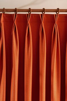 an orange curtain hanging on a wooden rod