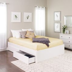 a white bed sitting in the middle of a bedroom next to a dresser and mirror