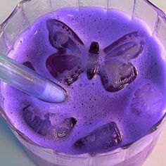 a purple drink with ice cubes in it and a spoon sticking out of the top