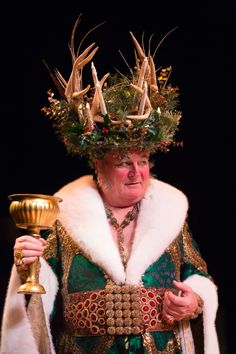 a man dressed in costume holding a golden cup and wearing antlers on his head