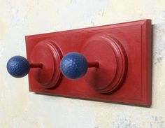 two blue balls are mounted to a red coat hook on a white and beige wall