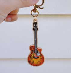 a guitar shaped keychain is hanging from a hook in front of a door