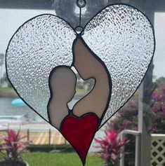 a stained glass window with a woman holding a baby in her arms and the shape of a heart