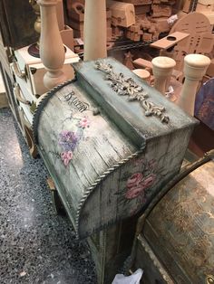 an old wooden box with flowers painted on it and some other items in the background