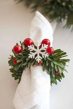 a napkin with holly and red berries on it is sitting on a white table cloth