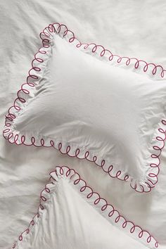 two white pillows with red piping on them