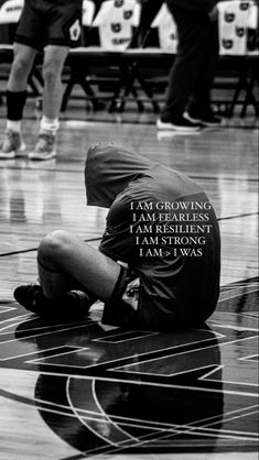 a man sitting on top of a basketball court with his head in his hands and the words i am growing