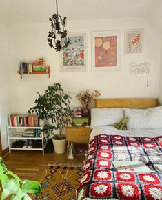 a bedroom with a bed, plant and pictures on the wall