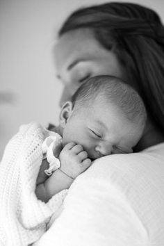 a woman holding a baby wrapped in a blanket while she sleeps on top of her