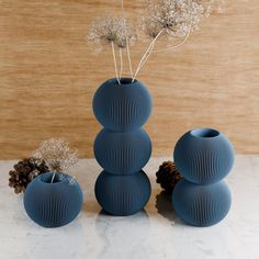 three blue vases sitting on top of a table next to pine cones and flowers