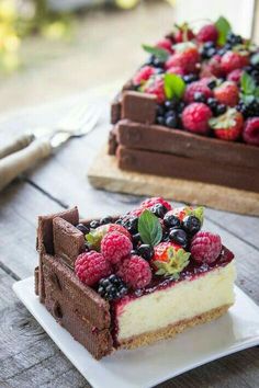 two slices of cheesecake with berries on top and chocolate cake in the back ground