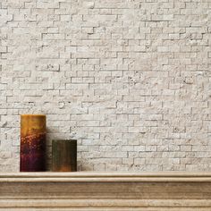 two vases sitting on top of a mantle in front of a white brick wall