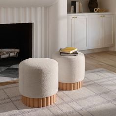 two white stools sitting on top of a rug in front of a fire place