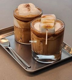 two glasses filled with ice cream sitting on top of a metal tray