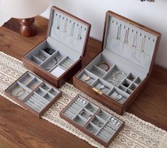 three wooden boxes with jewelry inside sitting on a table