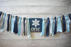 a one year old banner with snowflakes and ribbons hanging on a wooden wall