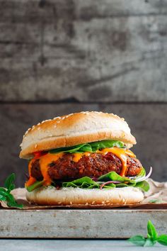 a meatball sandwich with lettuce, tomato and cheese on a wooden cutting board