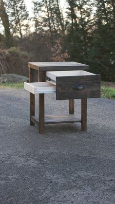 two wooden tables sitting in the middle of a gravel road with trees in the background