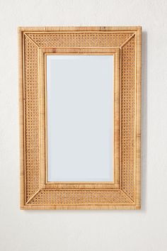 a wooden mirror hanging on the wall next to a white wall with a plant in it