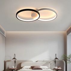 a bedroom with a bed and two lights on the ceiling above it, in front of a white wall