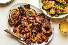 two plates filled with meat and onions next to a glass of beer on a table