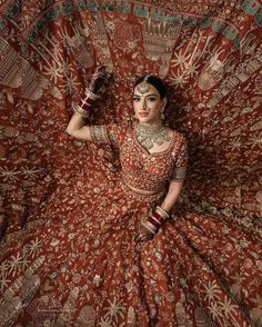 a woman in an orange and red sari is posing for the camera with her hands behind her head