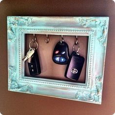 three keys are hanging in a blue frame on the wall next to a key holder