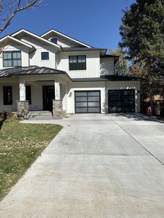 a large white house with two garages on the front and one car in the driveway