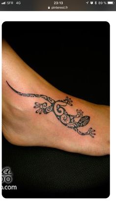 a tattoo on the foot of a woman with an ornate lizard and crossbones