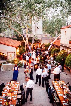 a group of people standing around tables with food on them and candles in the air