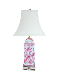 a pink and white table lamp with a shade on it's base, against a white background