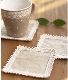 two small white doily sitting on top of a wooden table next to a cup