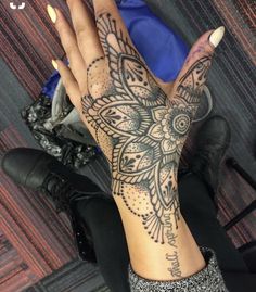 a woman's hand with an intricate tattoo on it